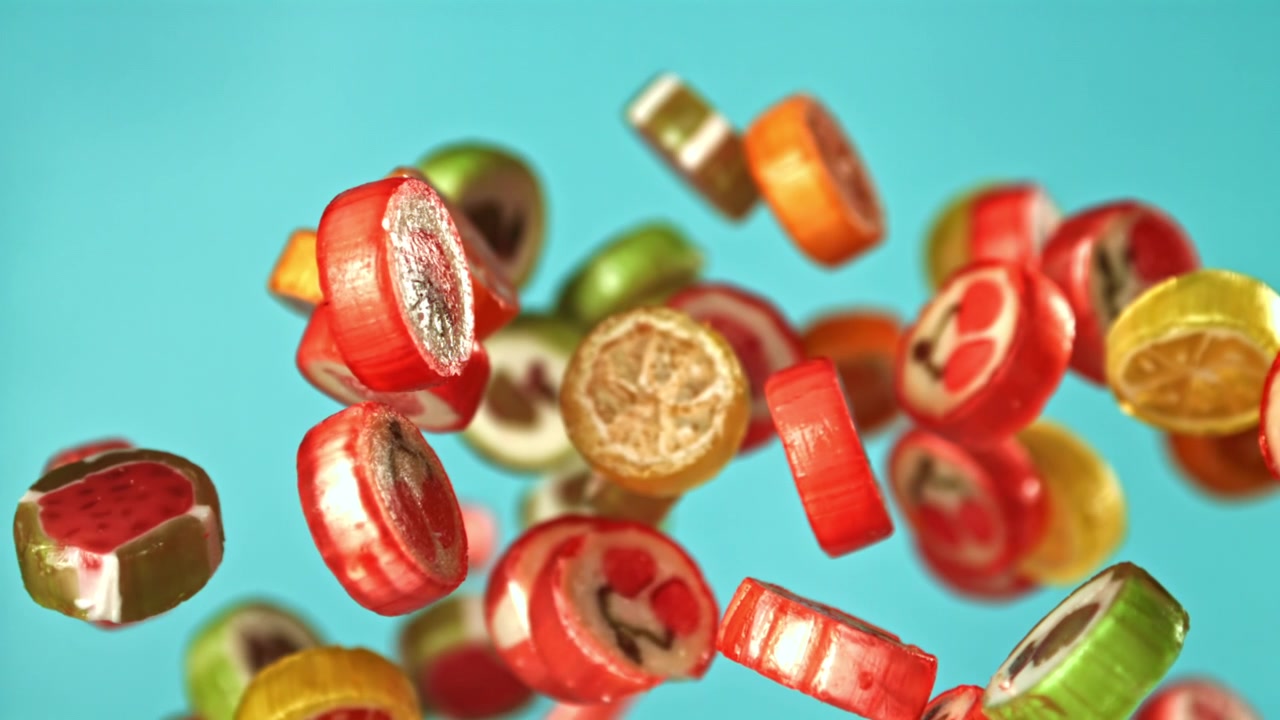 Farverigt frugtslik falder i slowmotion mod en blå baggrund
