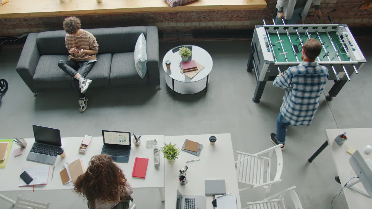 Coworking Space with People Working and Playing Foosball