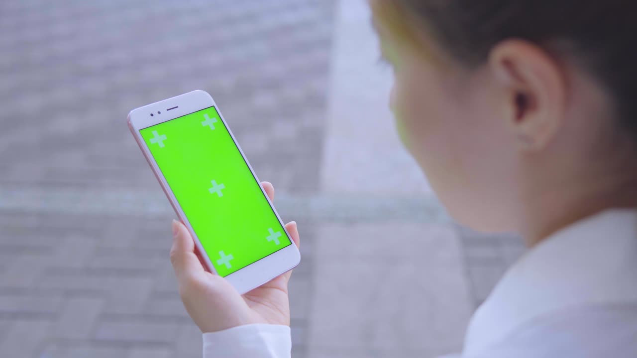 Business woman using smartphone with green screen on the street