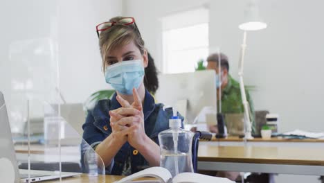 woman wearing face mask sanitizing her hands at office