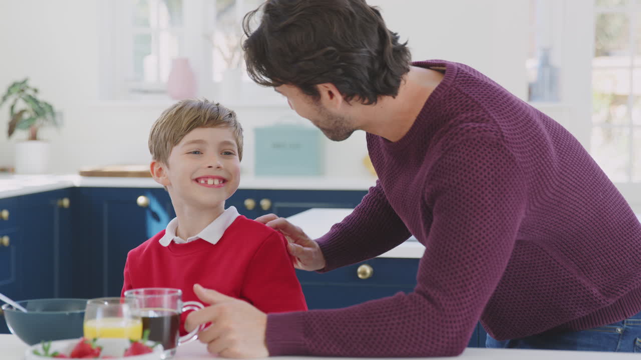 padre desayunando con su hijo vistiendo uniforme escolar en casa en la cocina