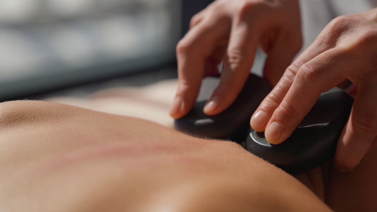 Close-up de Massagem com Pedras Quentes nas Costas de uma Pessoa
