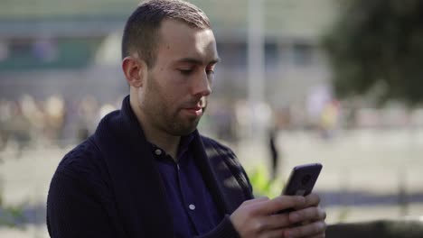 Cheerful-young-man-with-bristle-using-smartphone