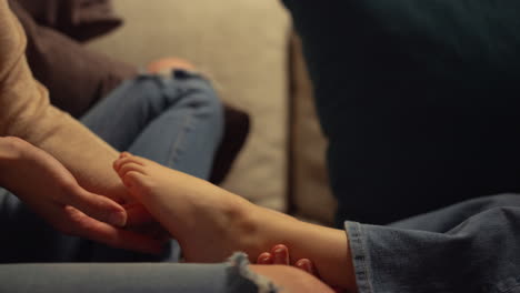 Mom-hands-tickling-kid-foot-indoors.-Unknown-mother-child-having-tender-moment.