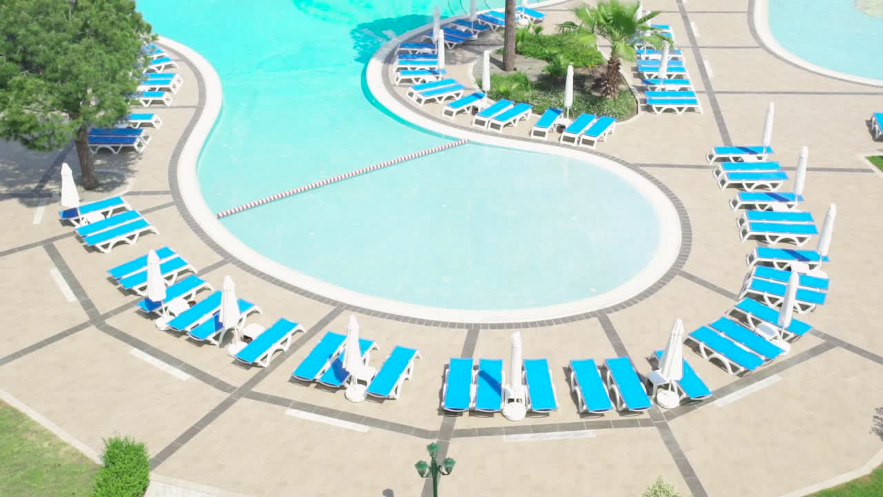 Hotel swimmingpool med liggestole og parasoller