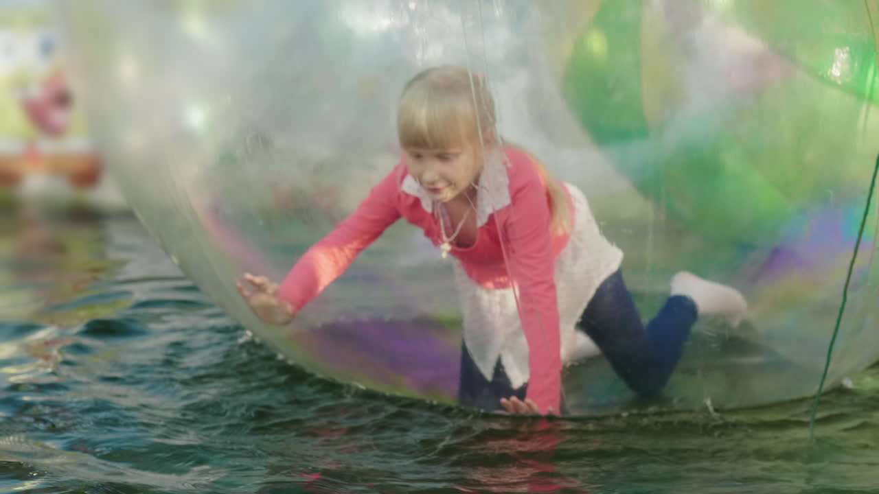 놀이공원에서 즐거운 시간 보내기 vnutki 투명 볼 소녀가 네발로 달리고 공이 수레에 떠 있습니다.