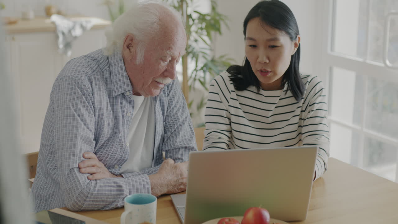 Elderly Man Learning to Use Laptop with Assistance