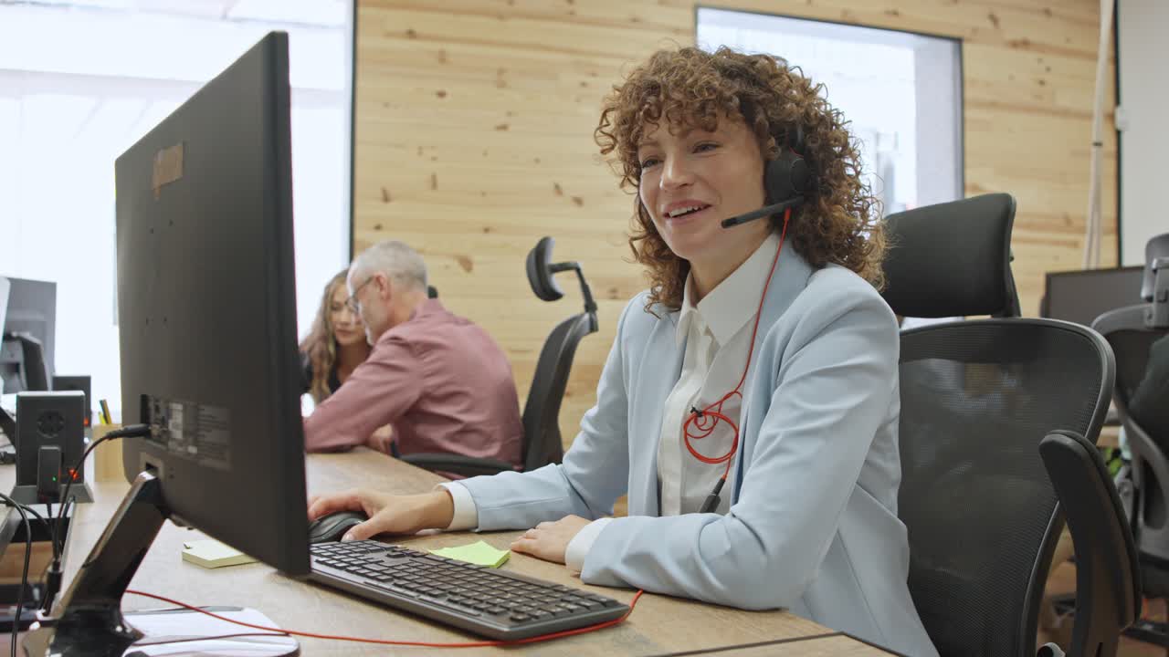 Businesswoman working at computer with headset in office