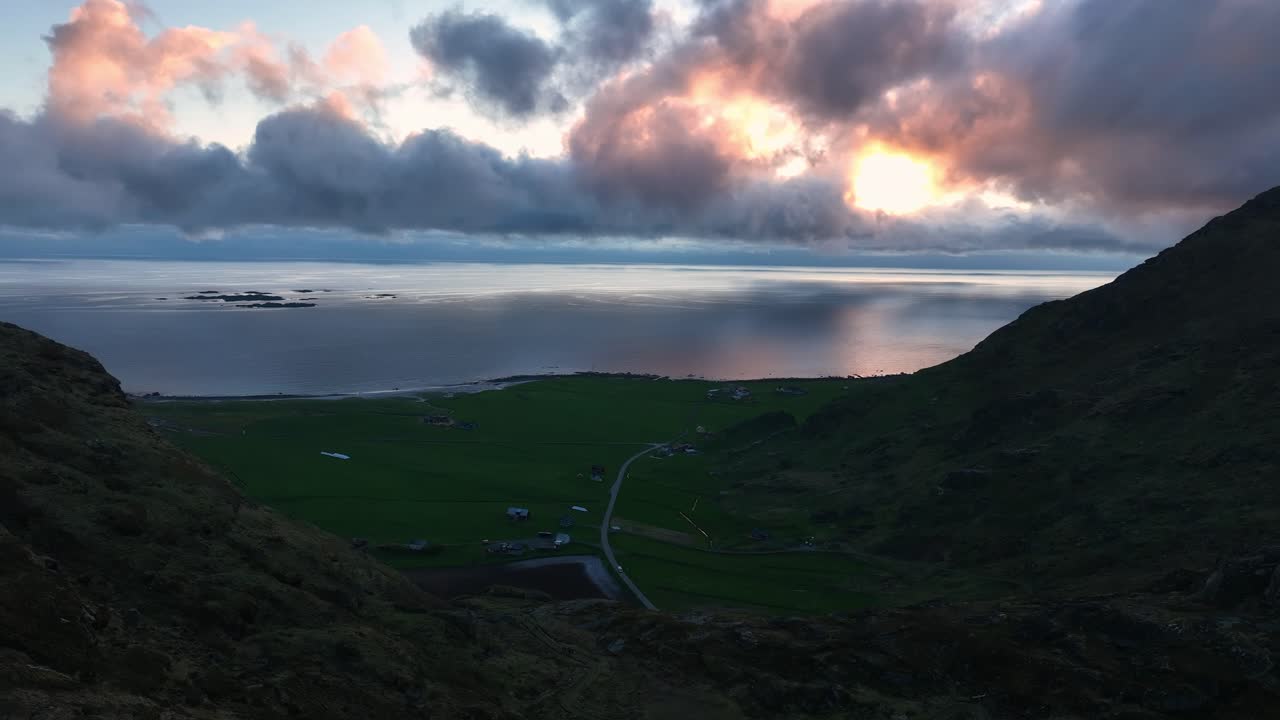 Cliffs and ridge of mountain Mannen passed by drone, revealing Utakleiv beach, ocean and pink clouds