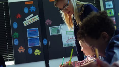 Teacher-helping-schoolkids-with-their-homework-in-classroom