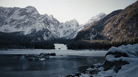 Capture-the-beauty-of-Fusine-Lake-against-a-backdrop-of-towering-mountains,-illuminated-by-the-golden-glow-of-a-setting-sun