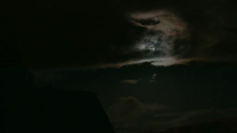 Timelapse-of-shining-full-moon-in-dark-clouds-in-East-Berlin,-Germany