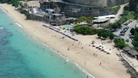 Hermosa-Vista-Aérea-De-Algunos-Visitantes-Tomando-El-Sol-Al-Atardecer-En-La-Playa-De-Melasti-En-El-Sur-De-Bali,-Indonesia