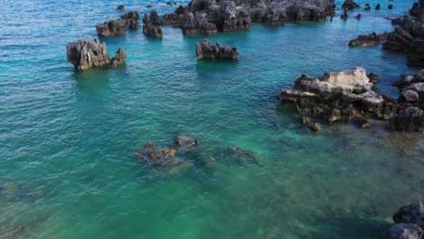 aerial view of sharp pointy rocks in turquoise water by tropical island