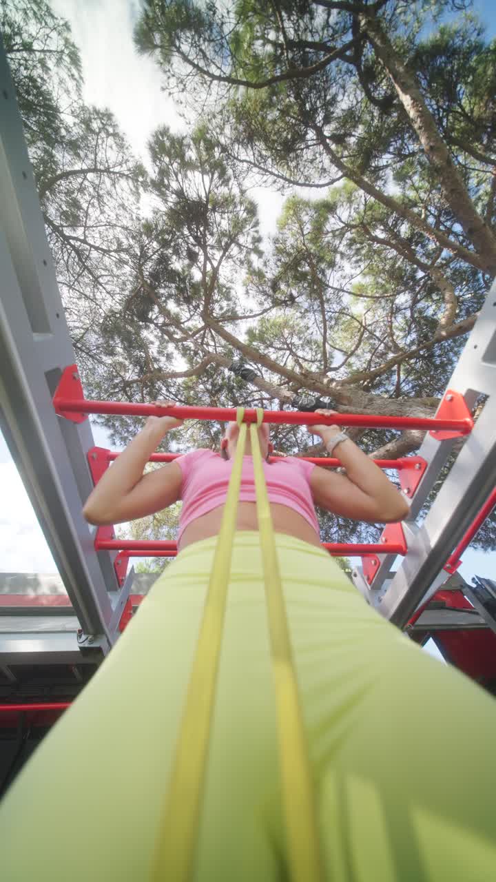 Woman Exercising on Monkey Bars with Resistance Band Outdoors