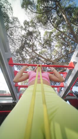 woman exercising on monkey bars with resistance band outdoors
