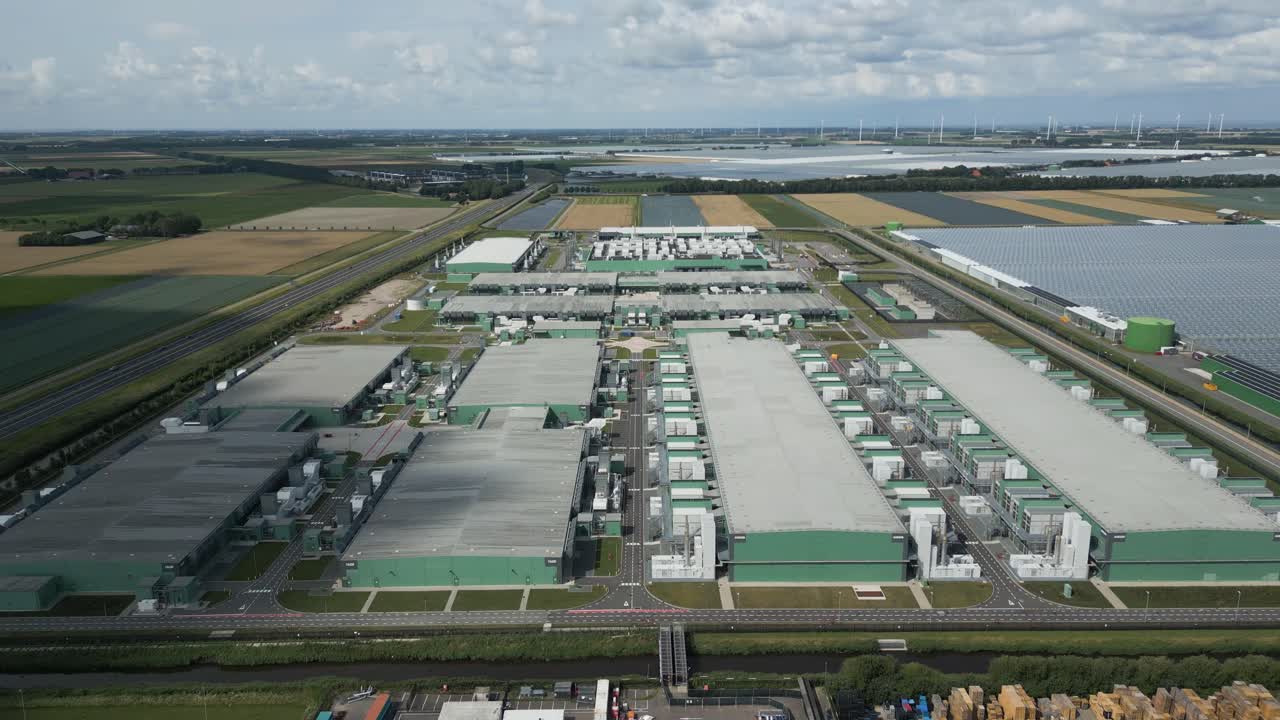 Drone footage of a large data center complex at Agriport Eemshaven, surrounded by farmland and sustainable energy facilities in the Netherlands