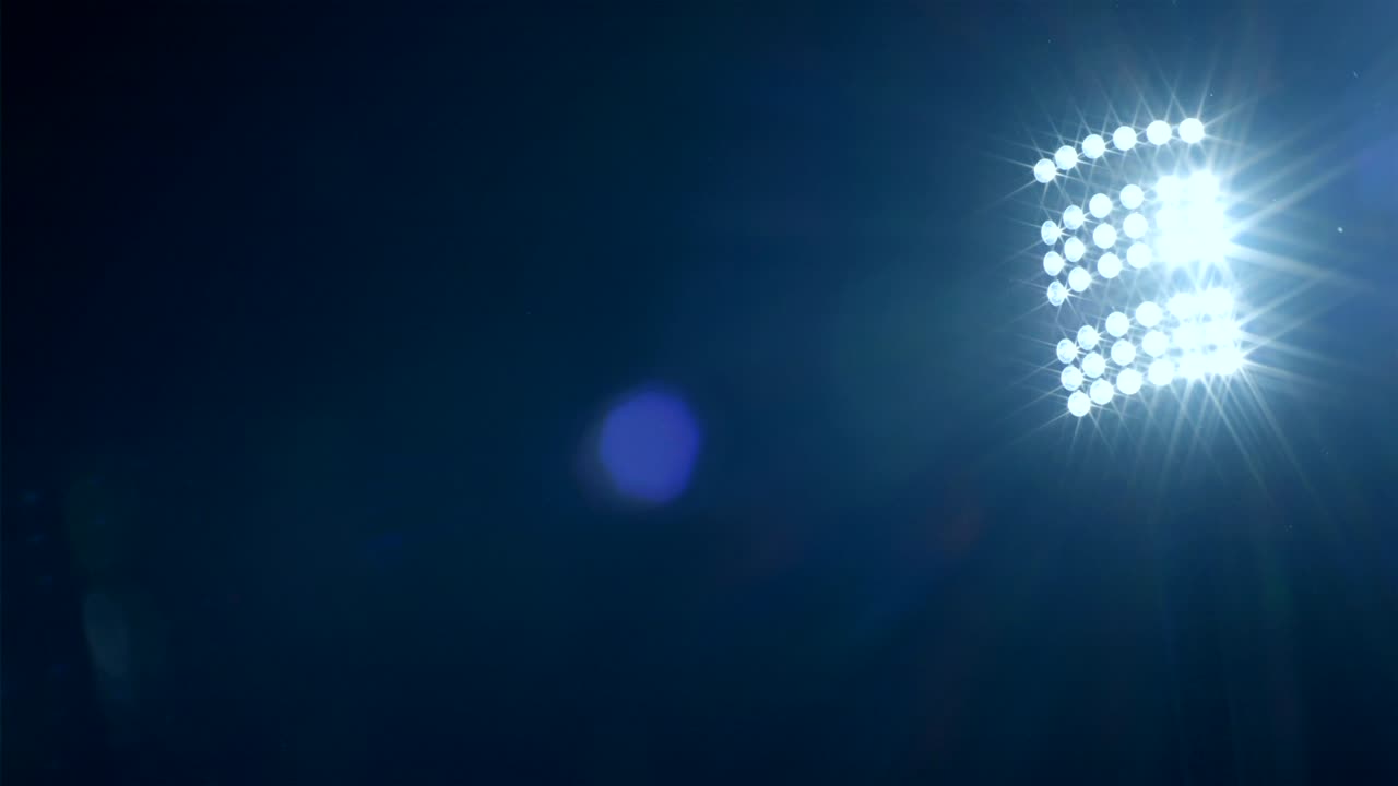 Sfondo delle luci dello stadio di calcio/sportivo contro il cielo scuro, con rete in primo piano, 4k