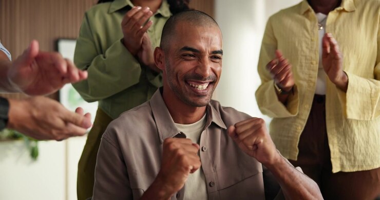 Uomo felice che festeggia il successo con i colleghi che applaudono in ufficio