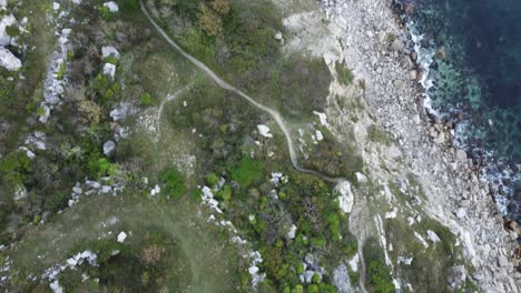 4K-Aerial-cinematic-landscape-shot-of-the-coast-on-the-island-of-Portland-during-sunset,-flying-over-the-beach-of-Church-Ope