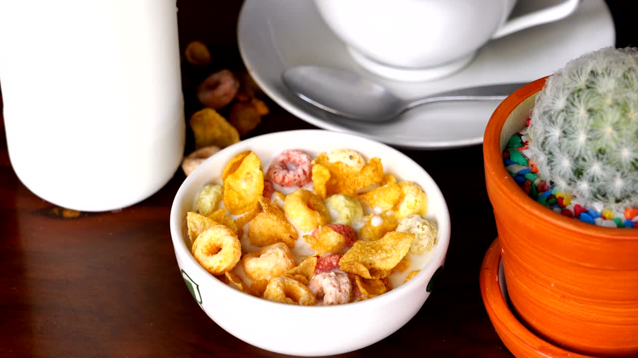 recoger y comer escamas de maíz de cereal y bucles de frutas de un cuenco blanco