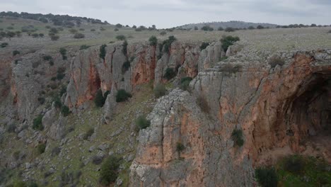 View-of-man-sitting-on-edge-of-cliff-as-drone-pulls-away-in-Nahal-Amud,-Israel