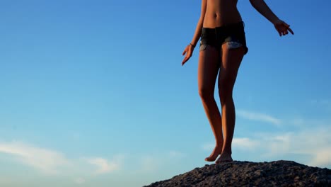 Volleyballspielerin-Steht-Auf-Einem-Felsen-Am-Strand-4k