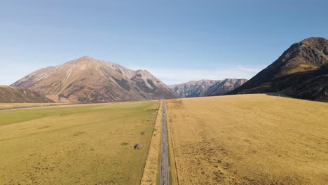 Approaching-vehicles-on-straight-road-within-towering-mountains