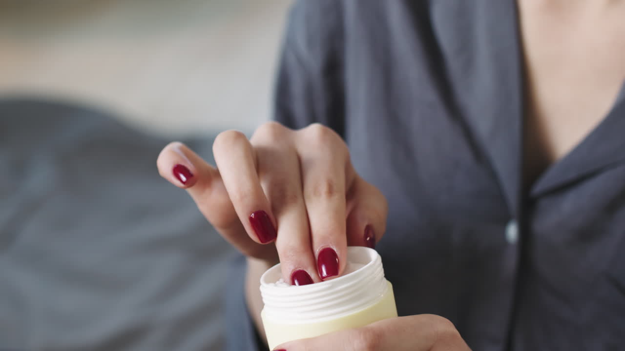 Woman In Silk Pajamas Applying Cream On Face