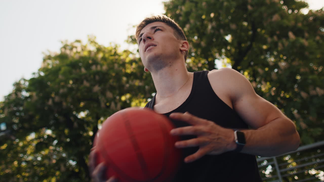 Athletic man in sportswear playing basketball game successfully throws ball into the basket ring