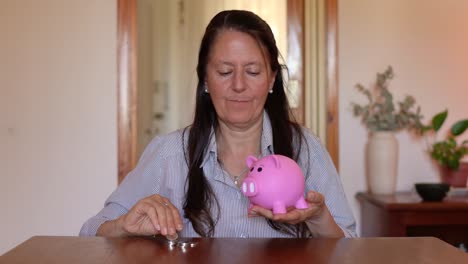 una mujer alegre depositando dinero en una alcancía - toma estática