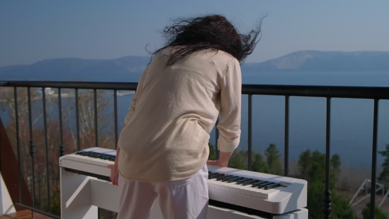 Woman Playing Piano on Balcony with Lake View