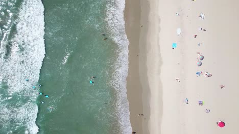 Birdseye-sunny-golden-sandy-beach-aerial-view-above-shimmering-turquoise-green-Pacific-ocean