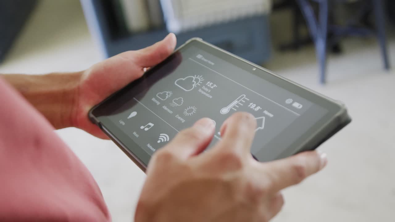 Biracial man spending time at home using tablet with smart home interface