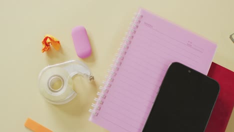 vídeo de un teléfono inteligente con espacio para copiar, cuadernos y equipos escolares sobre fondo amarillo