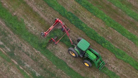 fields of abundance: tedding, raking, and a green tractor at work on a sunny day in british columbia