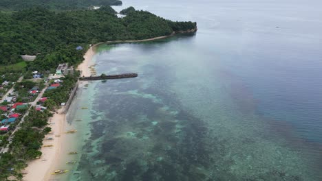 Impresionante-Vista-Aérea-De-La-Bahía-Transparente-Del-Mar-Con-Arrecifes-De-Coral-Vírgenes,-Playas-De-Arena-Blanca-Y-Comunidades-Boscosas-Cercanas-En-Virac,-Catanduanes