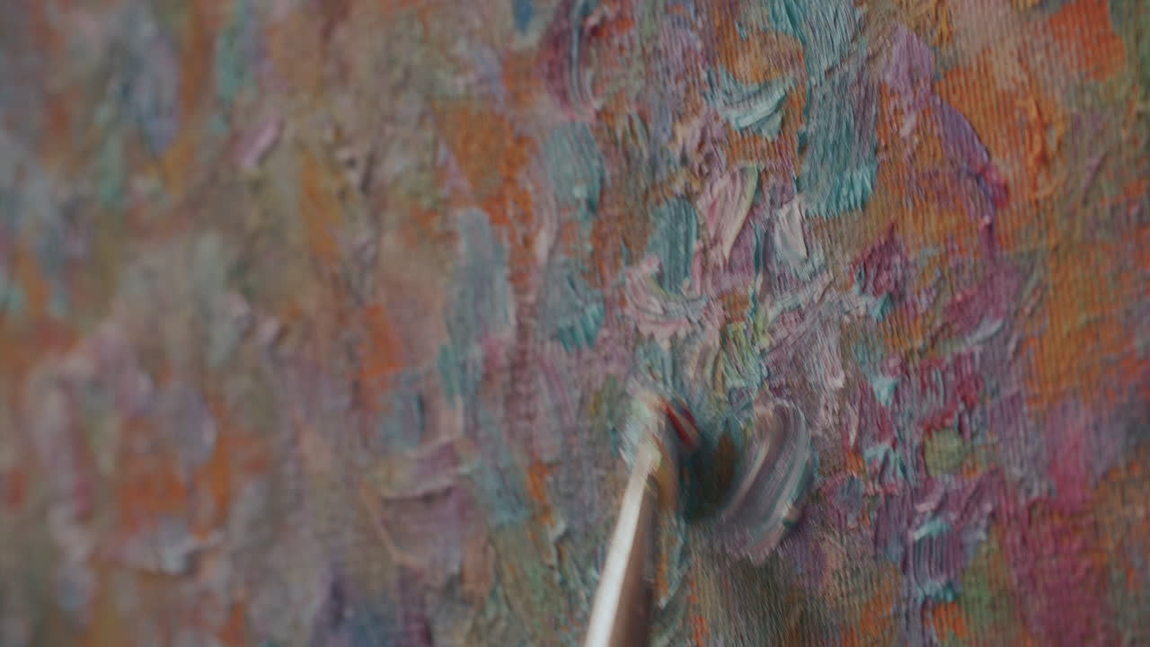 Detailopname van het aanbrengen van dikke penseelstreken verf op een gestructureerd canvasoppervlak