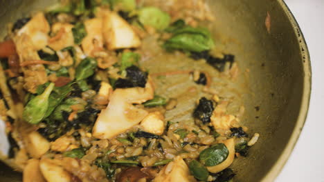 close up view of japanese food in the pan while the cook moves it with a slotted spatula