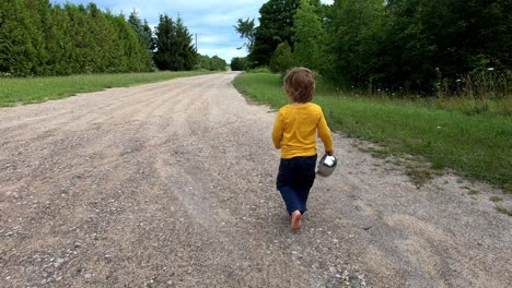 Süßes-Kaukasisches-Männliches-Kleinkind,-Das-Barfuß-Auf-Einer-Unbefestigten-Straße-Geht---Farmabenteuer-Während-Des-Kirschfestes-In-Traverse-City,-Leelanau-County,-Michigan,-Usa---Kamerafahrt