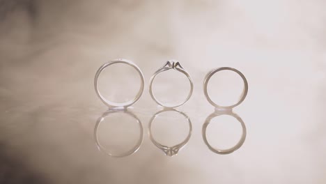 wedding and engagement rings lying on dark water surface shining with light