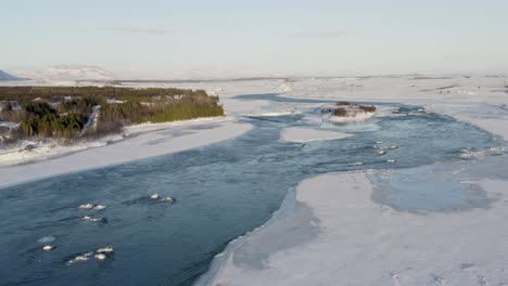 Aerial-flight-over-river-with-ice-barrier-in-Iceland-after-strong-snowstorm-at-night