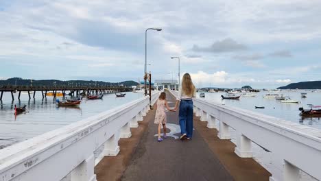 mother and daughter walking on a pier