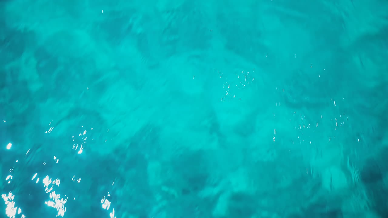 Agua transparente de un mar que refleja la luz del sol, vista desde el dron