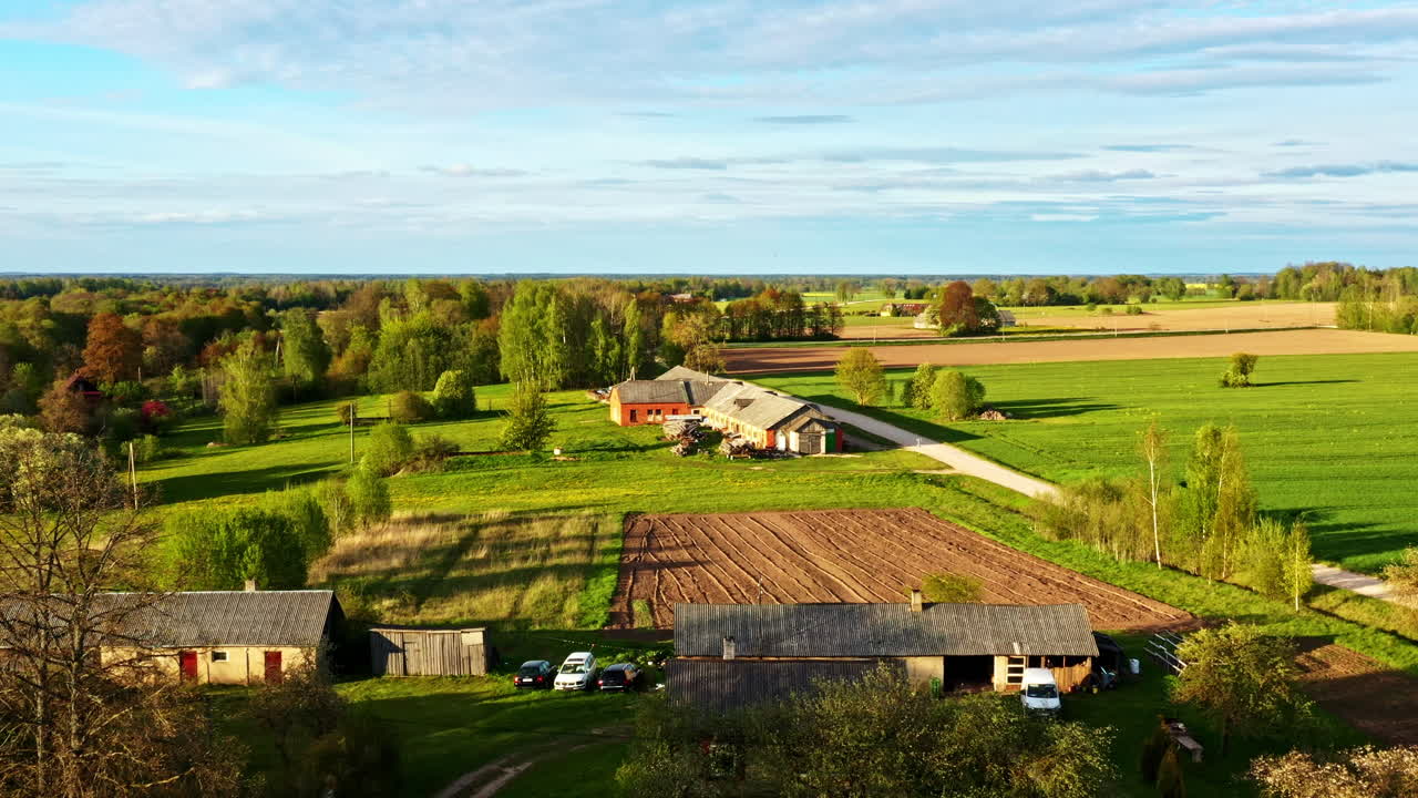 Wide Aerial View of Farmland With Fields, Trees, Dirt Roads and Farm Buildings