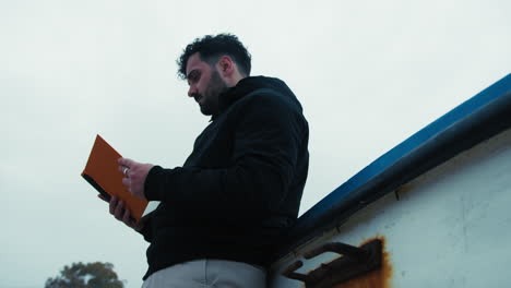 student reads his notes by the sea during a winter day