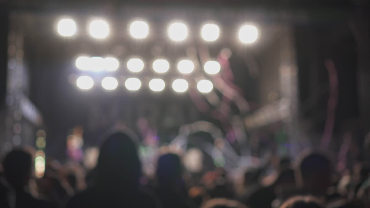 Confetti and flashing lights during live performance or concert above fans of music festival, blurry abstract view