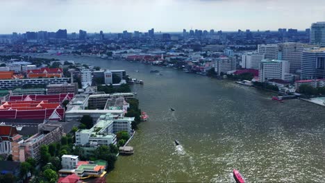 Boats-Sailing-At-The-Waterways-Of-Chao-Phraya-River-In-The-Cityscape-Of-Bangkok,-Thailand