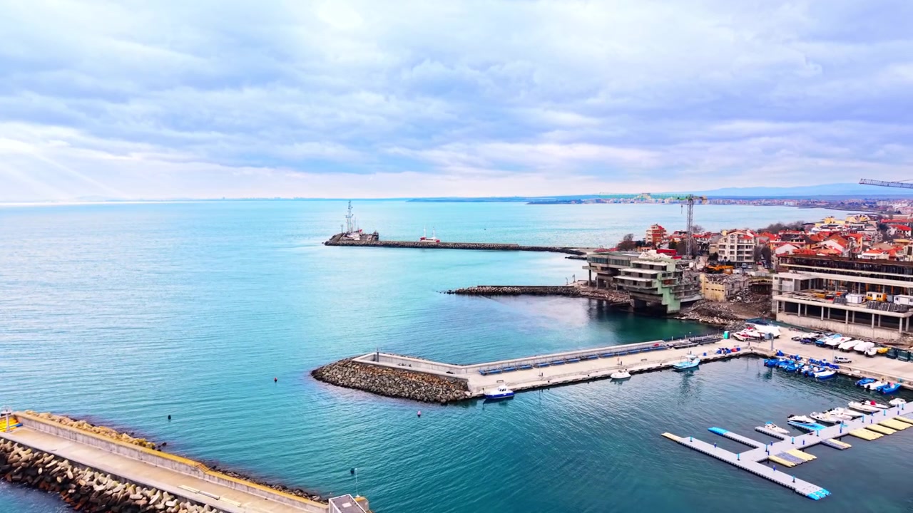 Vista aerea del porto turistico di una città costiera con frangiflutti, pontili galleggianti e costruzioni edilizie. Sviluppo portuale moderno e moli in pietra, Pomorie, Bulgaria