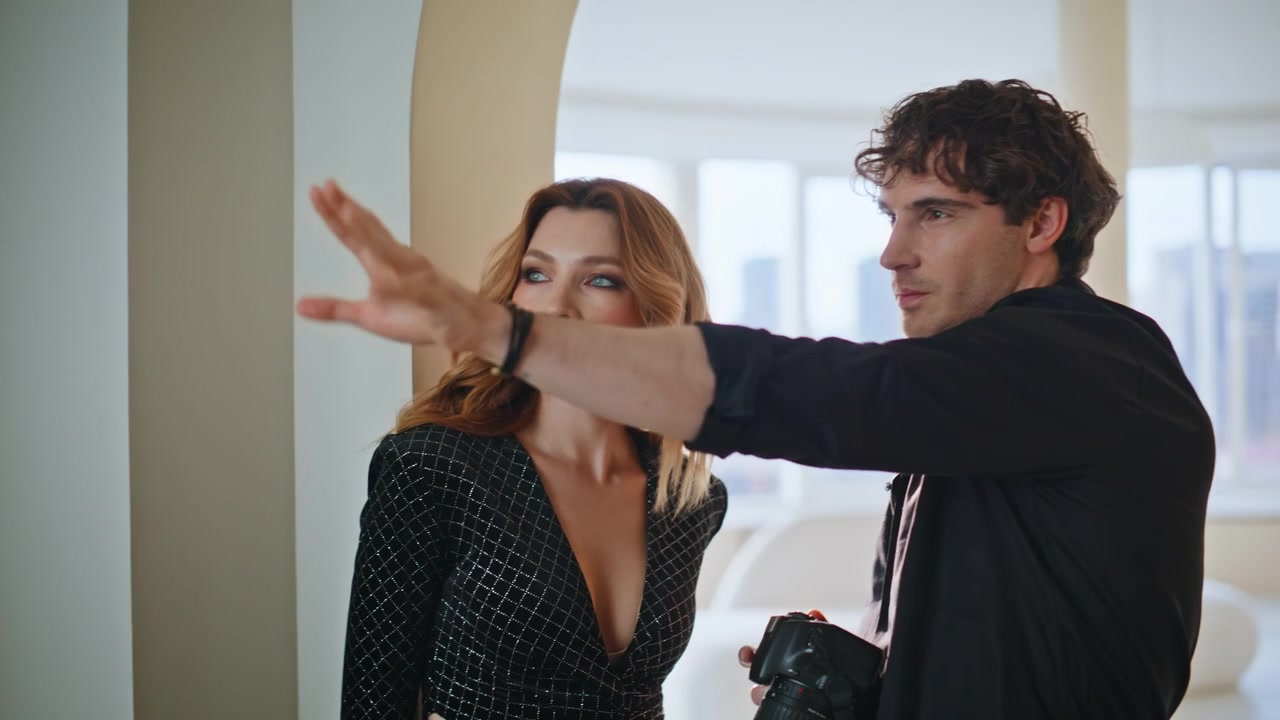 Fotografo che rivede le foto di una modella in un appartamento di lusso. Uomo che dirige un servizio fotografico di moda